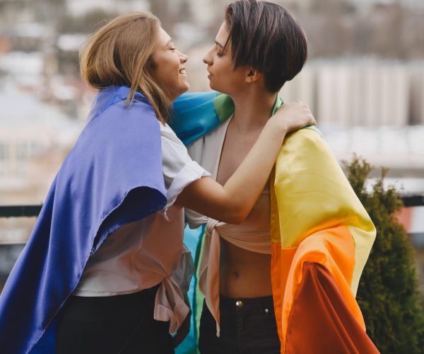 LGBT flag near girls. Girls of non traditional orientation. Hugs of lesbians.